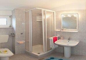 Un baño con cabina de ducha, lavabo, inodoro y espejo.