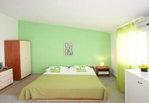 Una habitación con una cama, una mesita de noche, un escritorio, un armario y un cuadro en la pared.