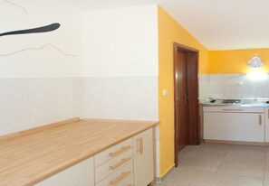 Une cuisine avec un plan de travail en bois, des armoires blanches et un mur jaune.