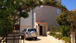 A two-story building with a paved driveway leading to a gated entrance. - Apartments Filip (Okrug)
