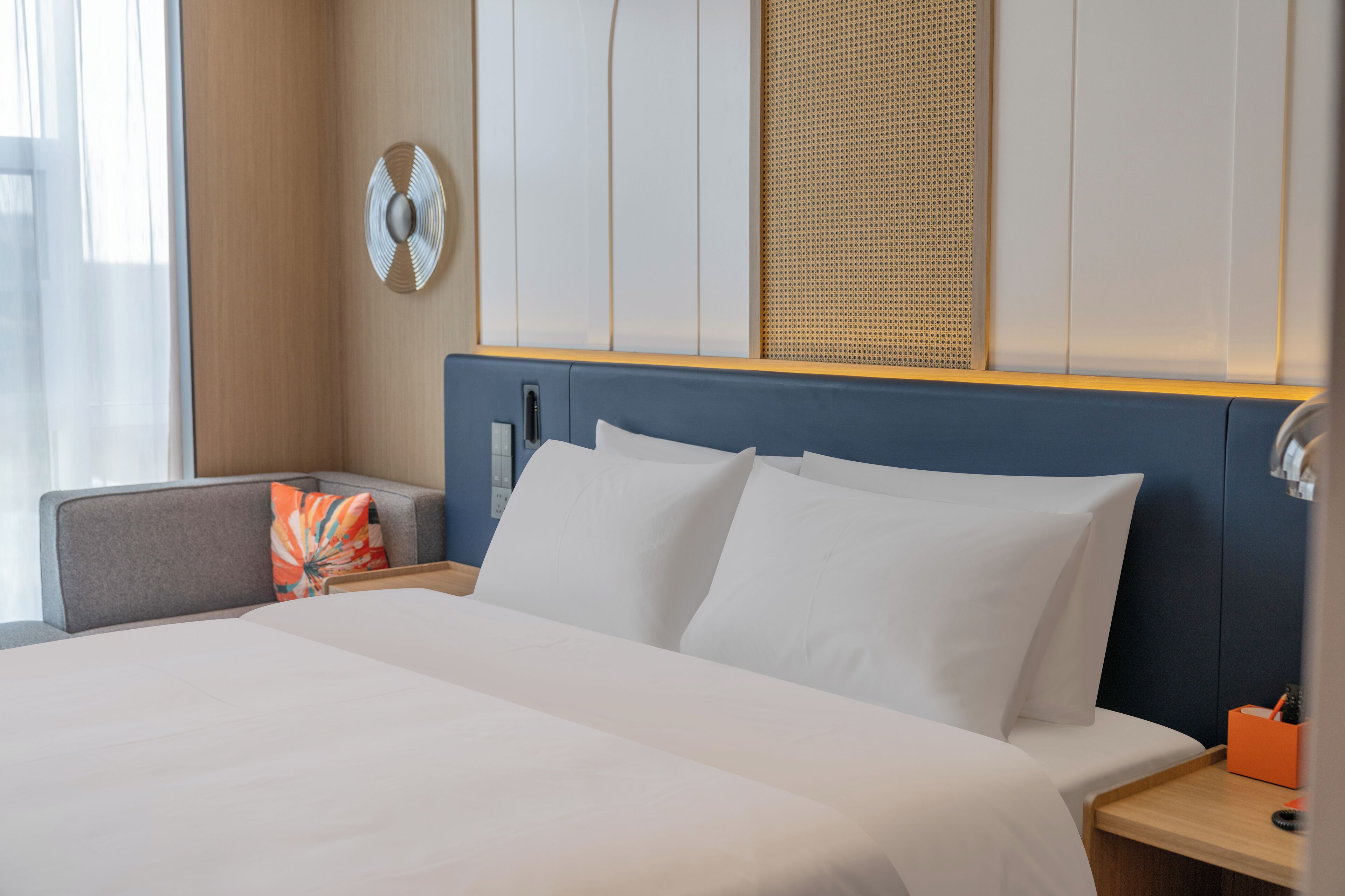 A hotel room with a large bed, a bedside table, a chair, and a wall-mounted decorative item.
