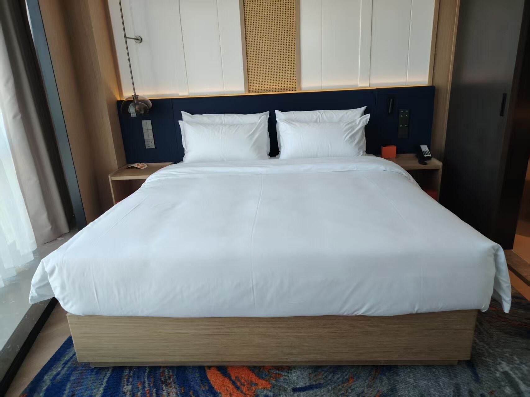 A large bed with white linens, a wooden headboard, and a blue accent wall.