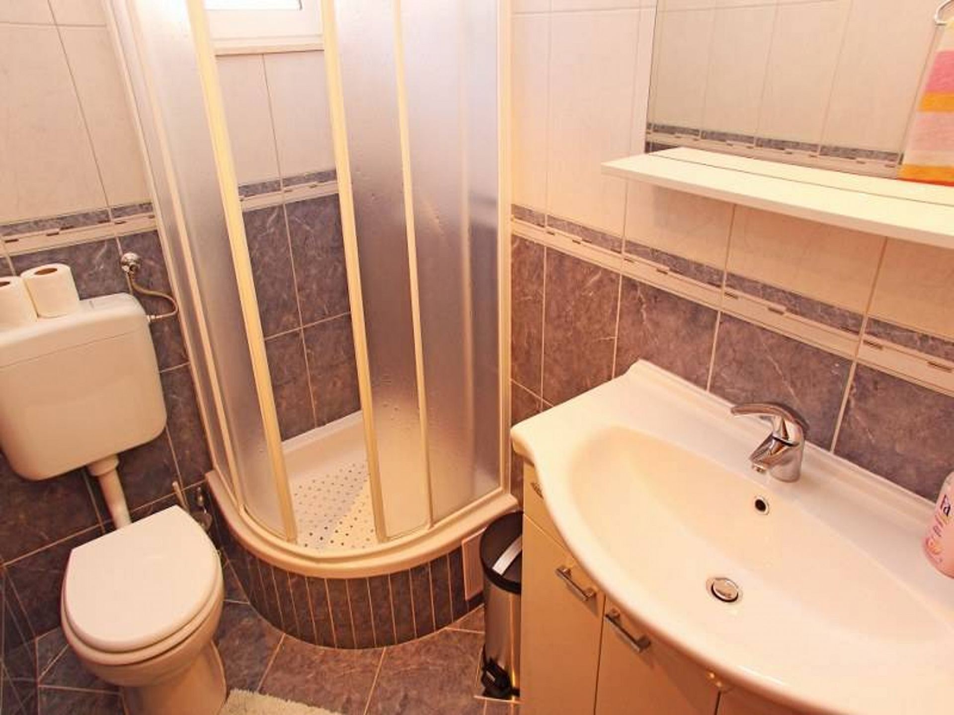 A bathroom with a toilet, a shower enclosure, and a sink.
