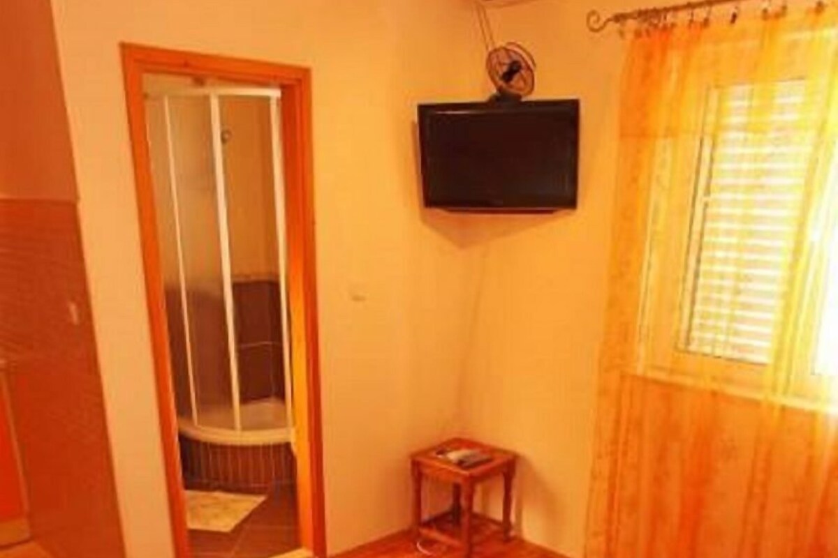 A hotel room with a bed, a television, a small table, and a window with curtains.