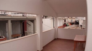 A narrow corridor with a small table and a chair, a white railing, and a view of neighboring buildings. - Apartments Marija (Hvar)