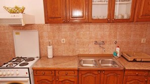 A kitchen with wooden cabinets, a stove, a sink, and a countertop. - Apartments Marija (Hvar)