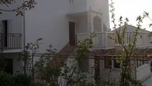 A white building with a balcony and a staircase leading to the entrance. - Apartments Marija (Hvar)