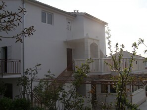 A white building with a balcony and a staircase leading to the entrance. - Apartments Marija (Hvar)