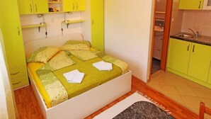 A small, bright room with a bed, a kitchenette, and a bathroom. - Apartments Marija (Hvar)