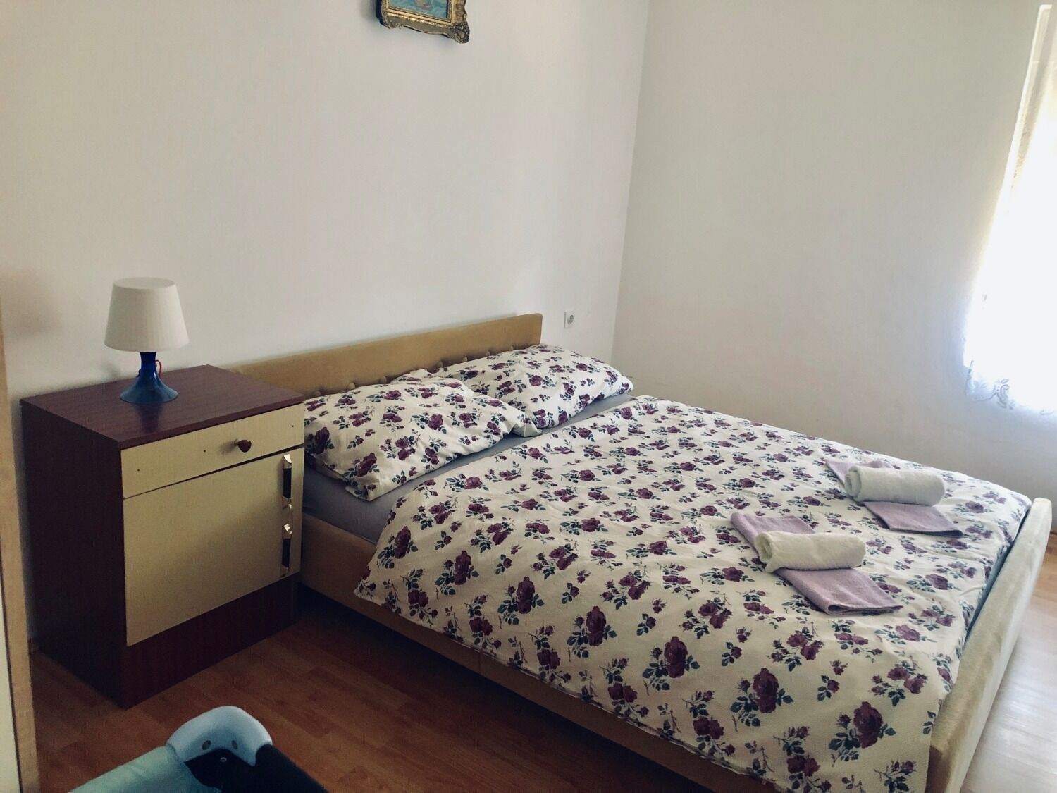 A single bed with floral bedding, a bedside table with a lamp, and a small chair.
