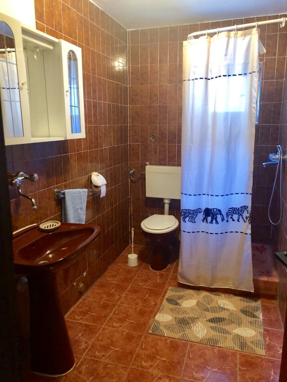 A bathroom with a sink, toilet, and shower area.