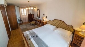 A bedroom with a large bed, a desk, a chair, a dresser, and a mirror. - Apartments Ela (Sutivan)