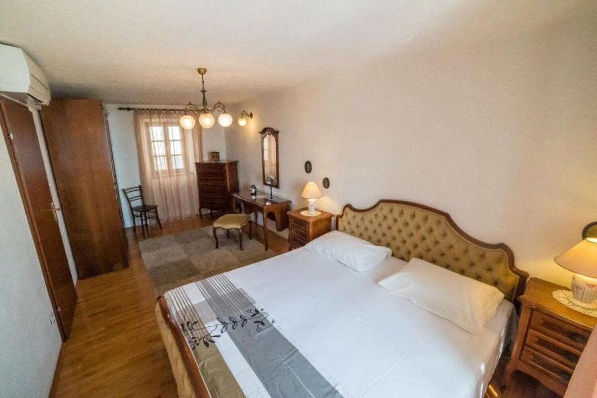 A bedroom with a large bed, a desk, a chair, a dresser, and a mirror.