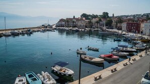 Un puerto deportivo con barcos amarrados, un paseo marítimo y edificios al fondo.