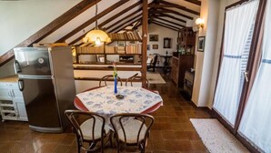 A cozy dining area with a table set for two, a refrigerator, and a bookshelf in the background. - Apartments Ela (Sutivan)