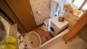 A compact bathroom with a sink, toilet, and washing machine. - Apartments Ela (Sutivan)