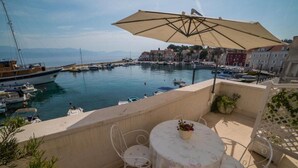 Una terraza con mesa y sillas, con vista a un puerto deportivo con barcos y edificios.