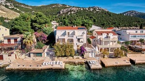 A coastal town with buildings near the water, featuring balconies and a clear view of the sea. - Apartments Sea Front (Slivno)
