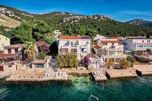 A coastal town with buildings near the water, featuring balconies and a clear view of the sea.