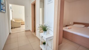 A hotel room with a bed, bedside table, and a potted plant. - Apartments Sea Front (Slivno)