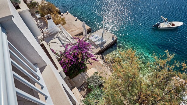 A balcony with a clear view of a boat on the water, a pool, and surrounding vegetation. - Apartments Sea Front (Slivno)