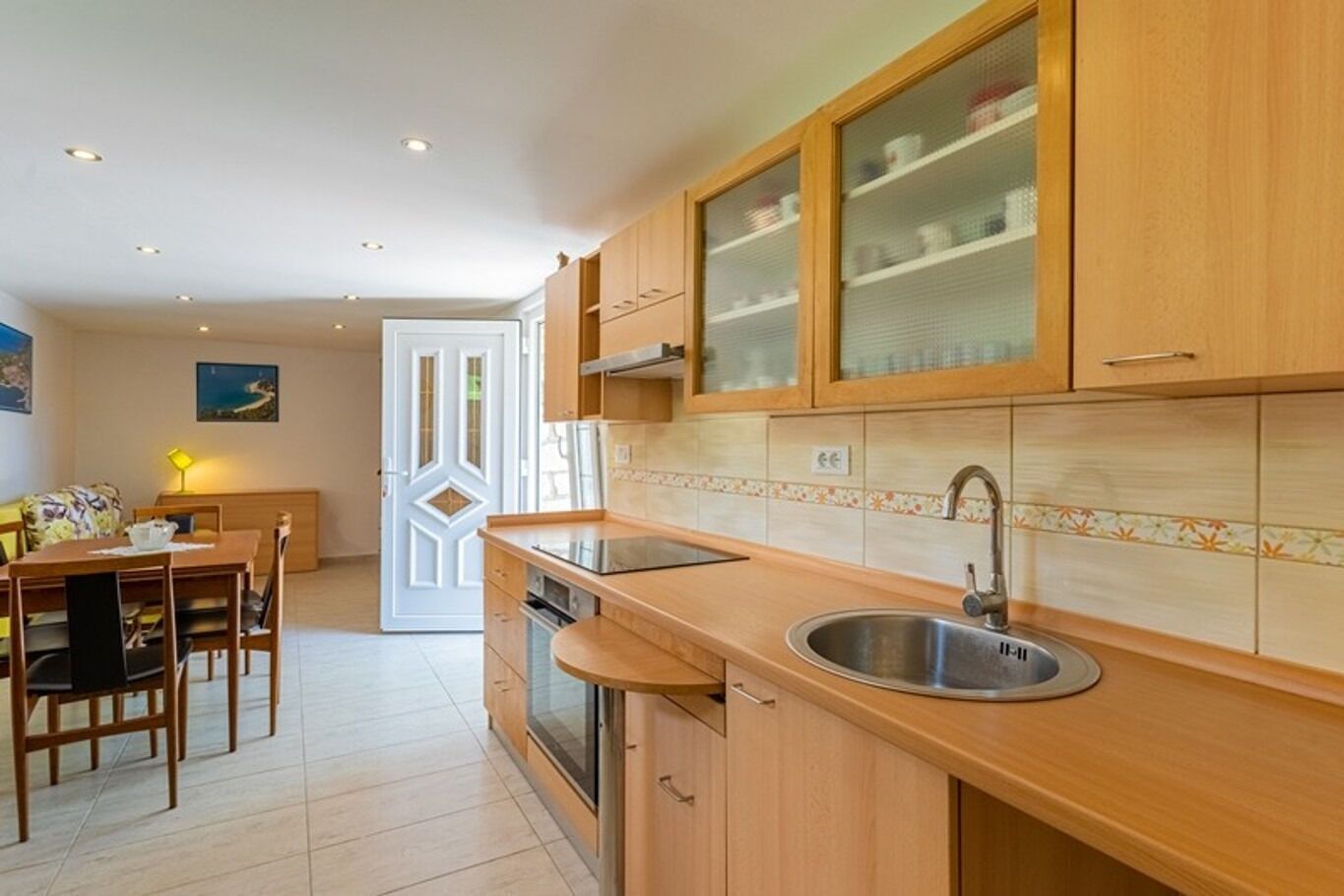 Cocina compacta con armarios de madera, un lavamanos y un comedor con mesa y sillas.