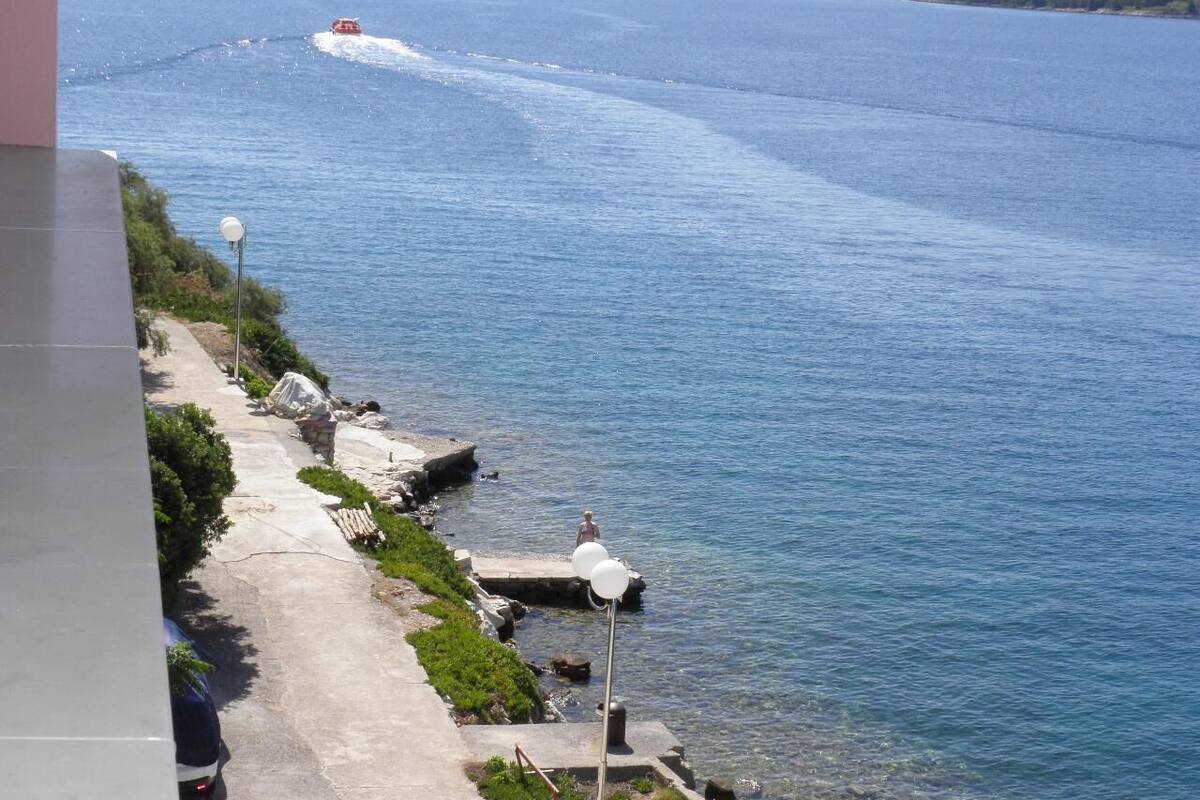 Une promenade en bord de mer offrant une vue dégagée sur l’océan, une vedette de sauvetage et des collines lointaines.