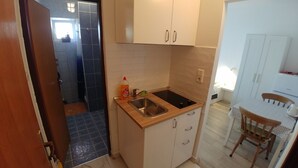 Eine kompakte Küche mit Spüle, Schränken und einer kleinen Essecke mit Tisch und Stuhl.
