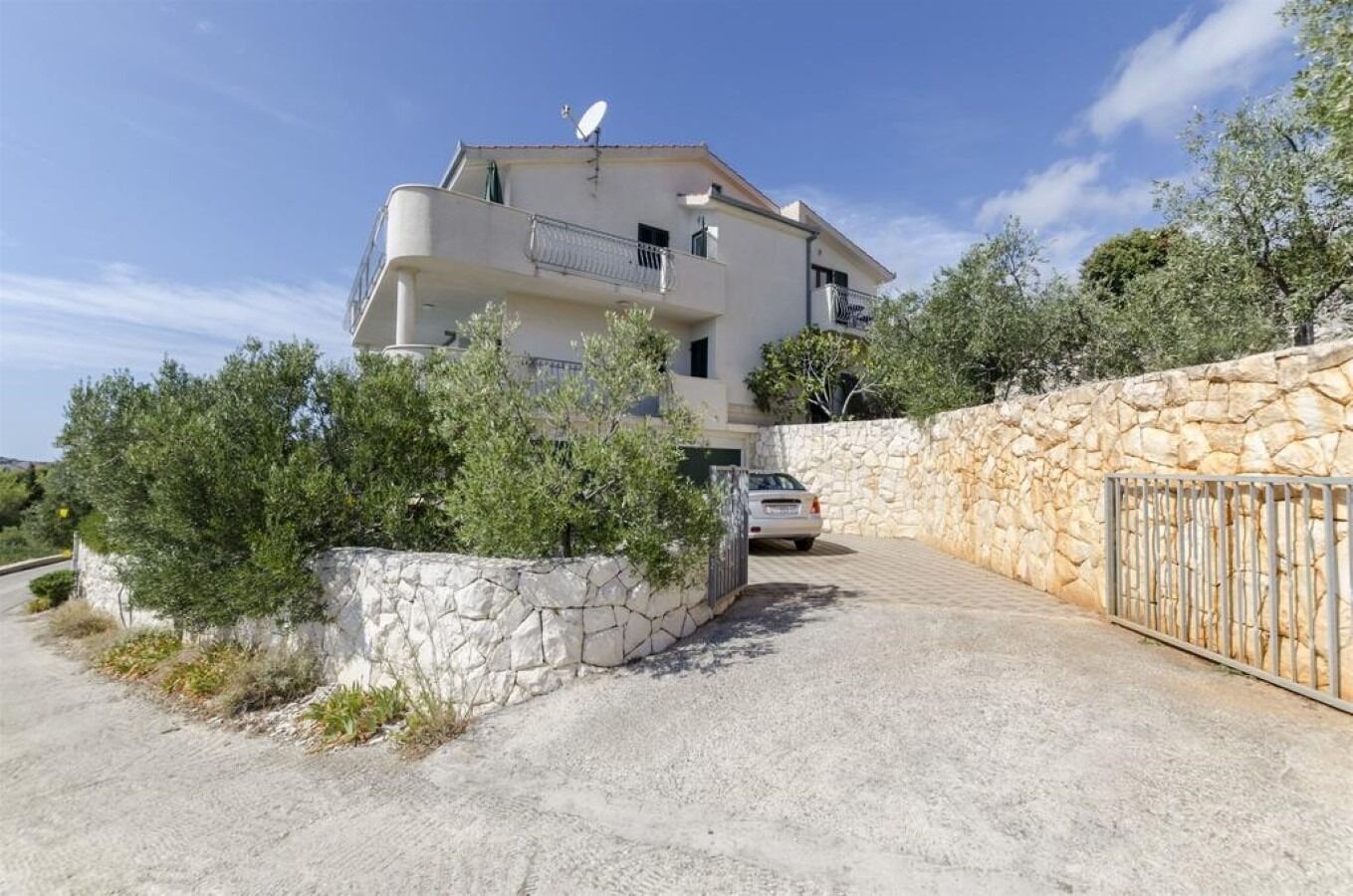 A two-story house with a stone wall and a gated driveway.