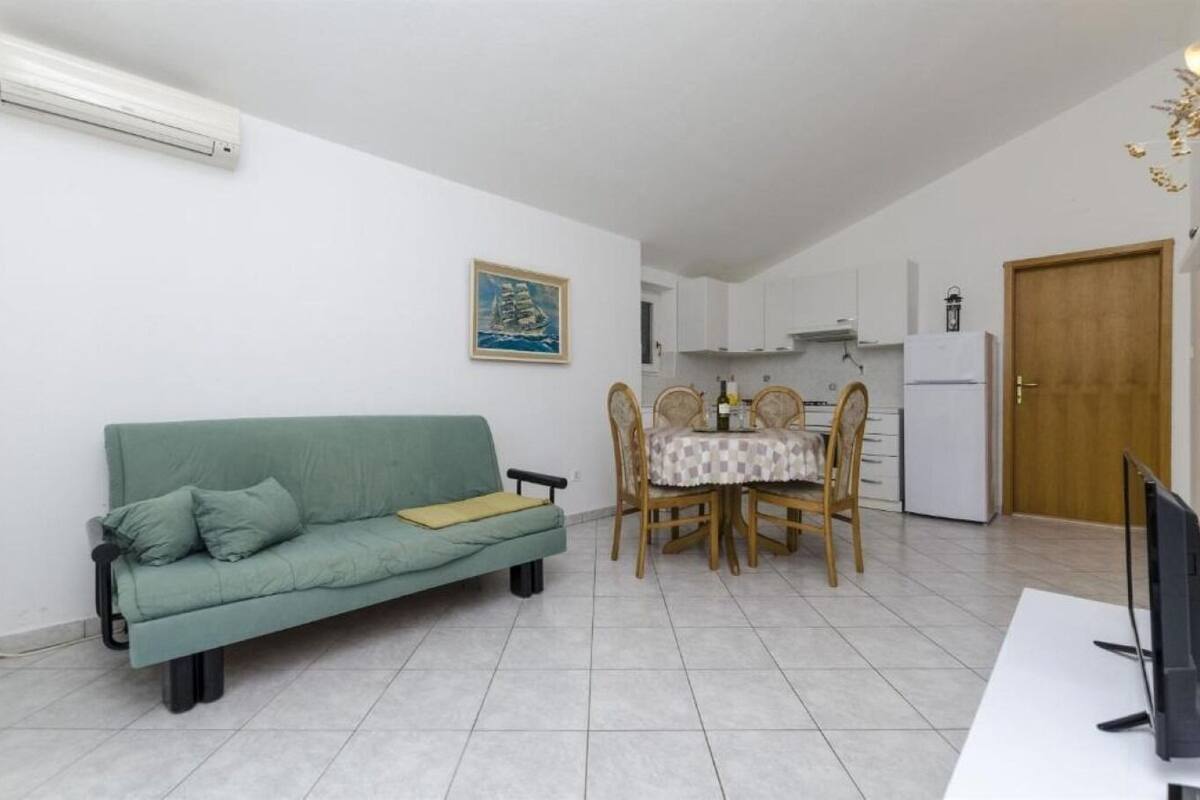 A compact living space with a sofa, dining table, chairs, and a kitchen area.