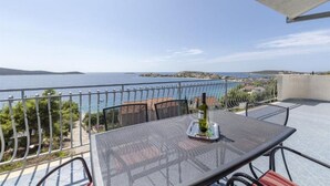 Un balcon avec une table et des chaises, offrant une vue sur la côte.