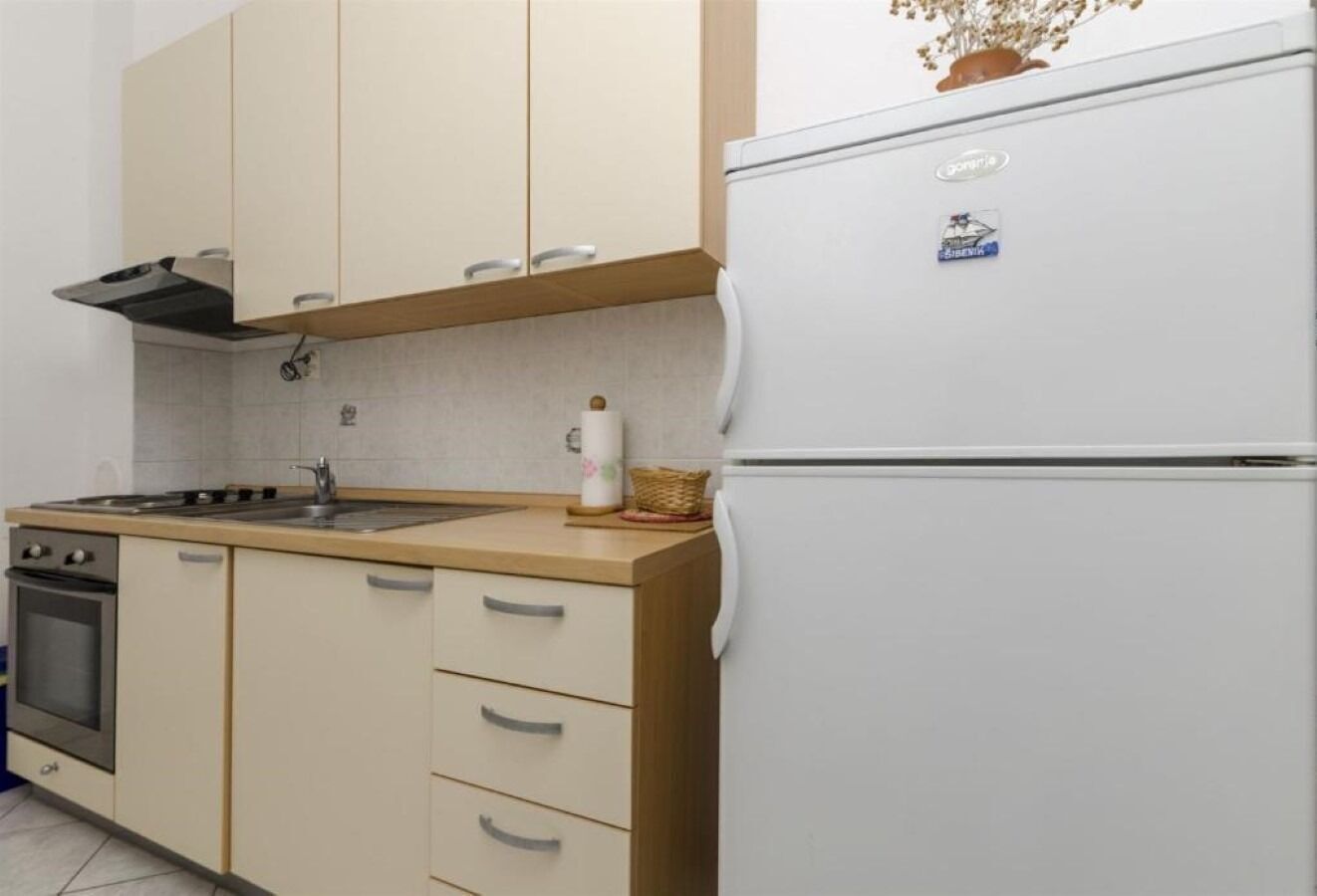 A kitchen with beige cabinets, a white refrigerator, a stove, and a sink.