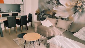 A modern living room with a sofa, a coffee table, and a dining area with chairs and a table. - Apartment Marijo (Makarska)