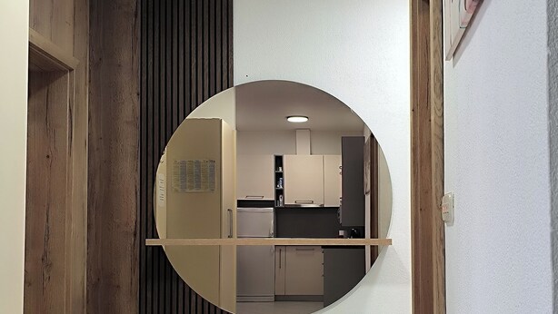 A hallway with a round mirror reflecting a kitchen area. - Apartment Marijo (Makarska)