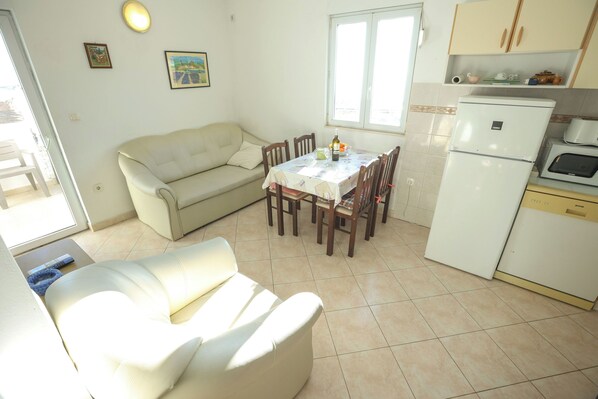 A compact living space with a dining table, a sofa, a refrigerator, and a microwave. - Apartments Teo (Privlaka)