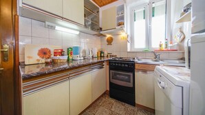 A compact kitchen with white cabinets, a stove, and a sink. - Apartment Nedjeljka (Postira)
