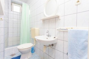 A bathroom with a toilet, sink, and shower area. - Apartments Tomislava (Makarska)