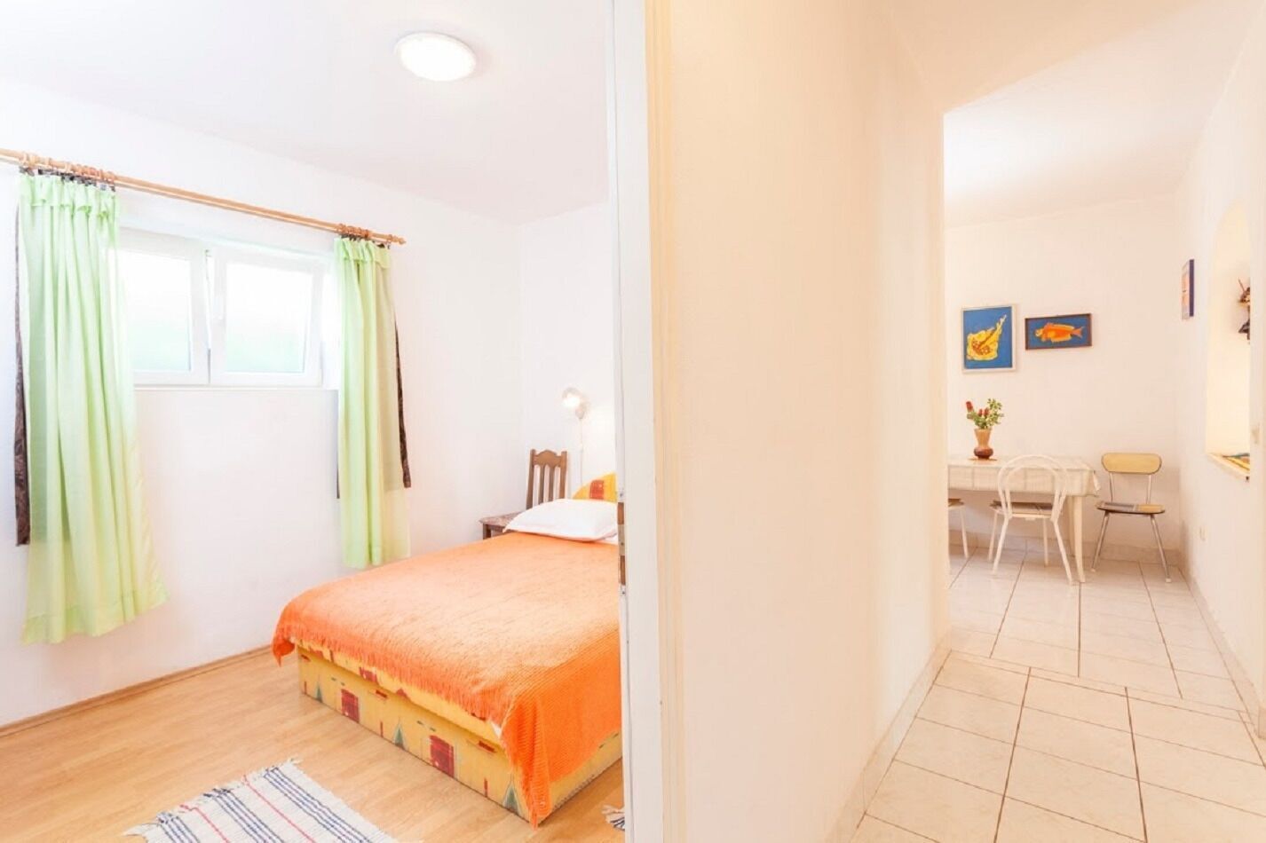 A bedroom with a bed, a window with curtains, a bedside table, and a lamp.