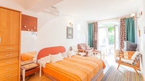 A bedroom with a bed, a desk, a chair, a television, and a wardrobe. - Apartments Tomislava (Makarska)