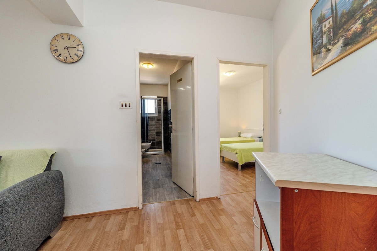A room with a bed, a desk, and a clock on the wall.