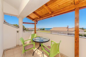En balkon med træloft, grønne stole og et glasbord.