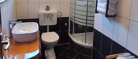 Ein Badezimmer mit weißem Waschbecken, Toilette und Duschkabine aus Glas.