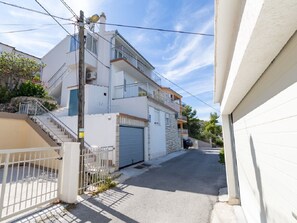A two-story residential building with a garage door, a staircase, and a balcony. - Apartments Petar (Trogir)