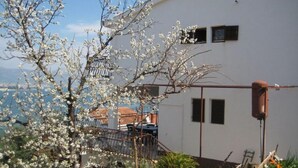 A white building with a metal staircase and a view of the sea. - Apartments Petar (Trogir)