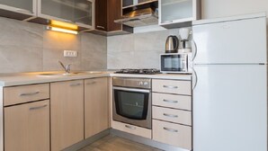 A modern kitchen with a built-in oven, microwave, and refrigerator. - Apartments Petar (Trogir)