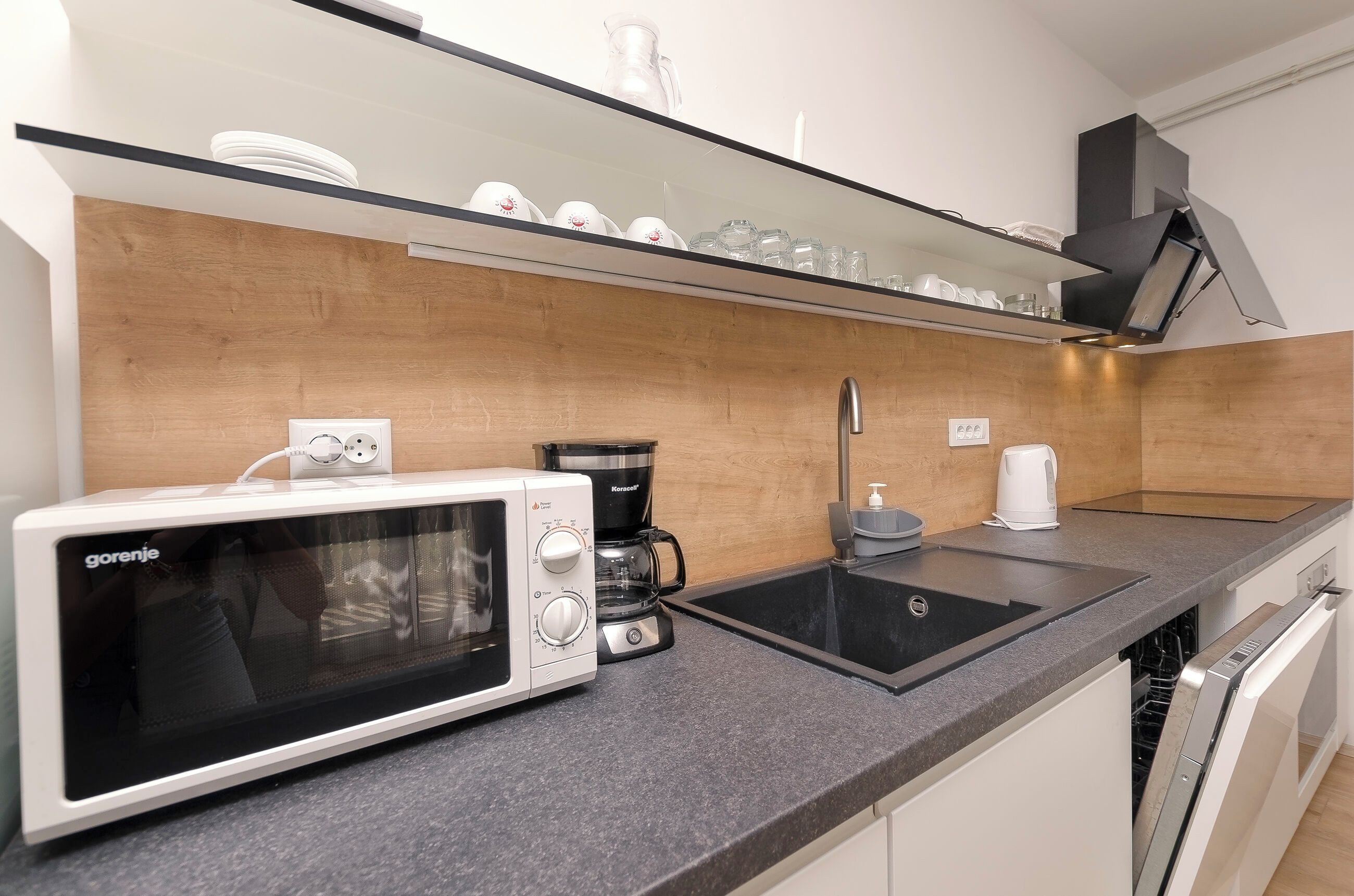 A compact kitchen with a microwave, coffee maker, and a sink.