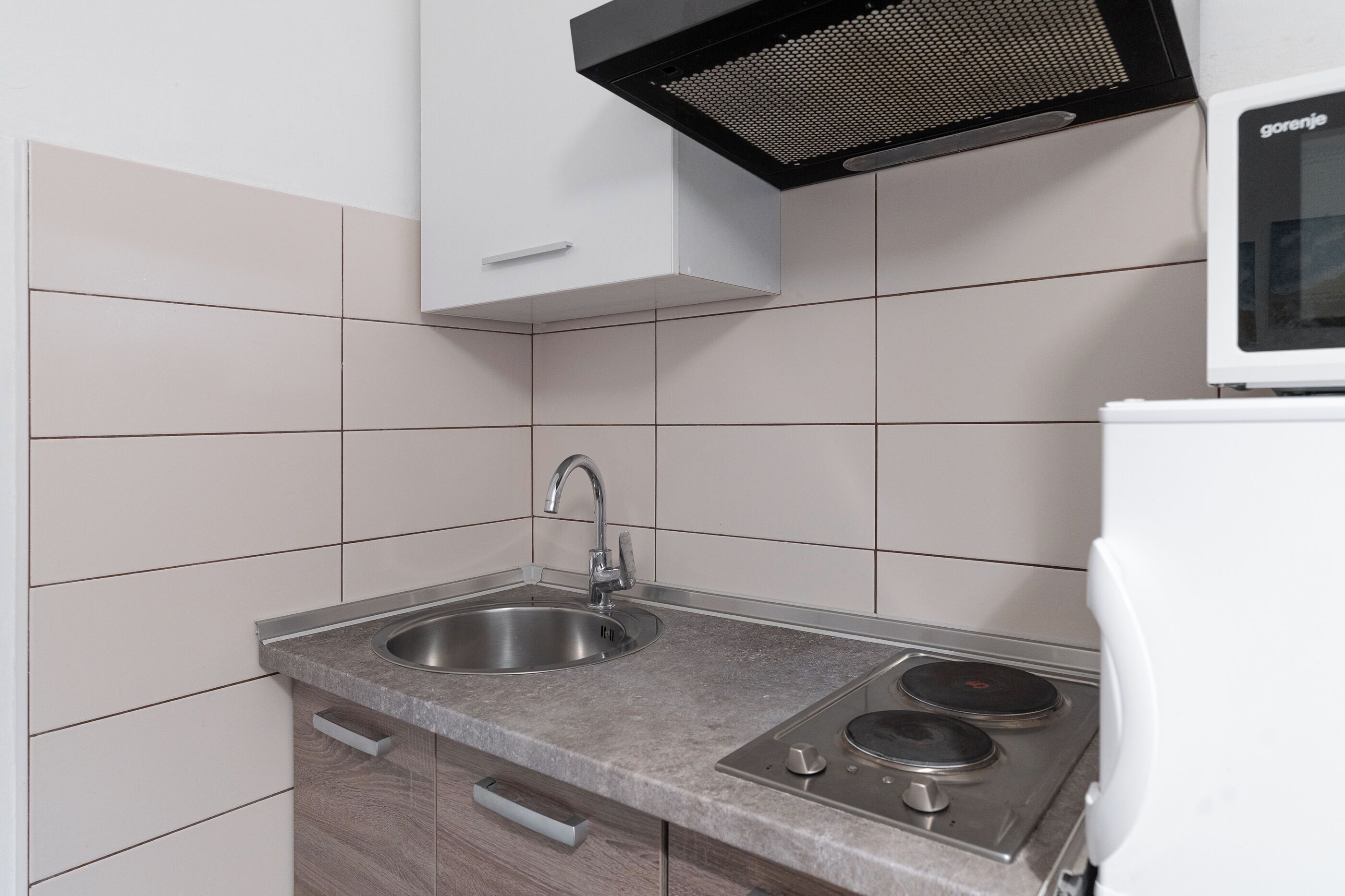 A kitchen with a stainless steel sink, a stove, and a microwave.