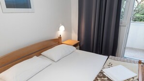 Habitación de hotel con una cama individual, una mesita de noche, una lámpara y vistas al exterior.