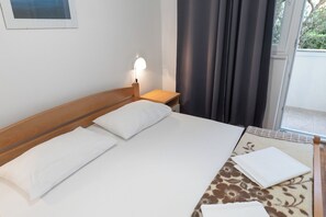 A hotel room with a single bed, a nightstand, a lamp, and a view of the outdoors. - Apartments Pere (Povljana)