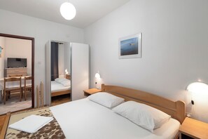 Une chambre d’hôtel comprenant un lit, des lampes de chevet, un bureau avec une chaise, une télévision et un tableau au mur.